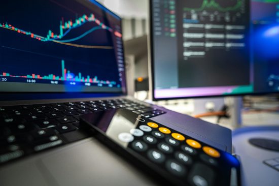 Close-up view of financial analysis on laptop and screen with calculator for business strategy.