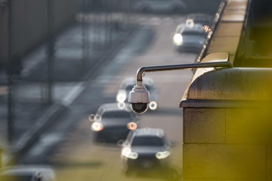 CCTV camera monitoring city traffic on a busy road with blurred vehicles in the background.